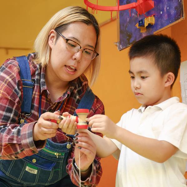 けん玉を教えるスタッフと子ども
